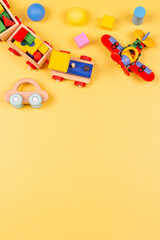 Baby kids toys. Wooden train, cars, plane, colorful blocks and balls on yellow background. Top view, flat lay