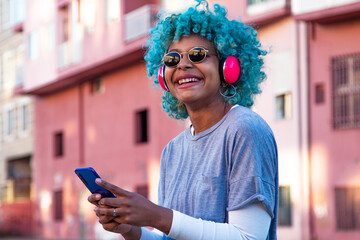 happy smiling girl with mobile phone and headphones enjoying in the street outdoors