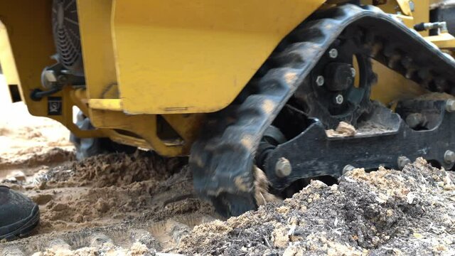 strain cutter wheel chain close view as it moves forward.
A layer of chips and sand can be seen under the stump cutter wheel chains or tracks