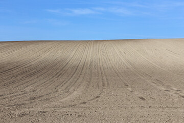 Naklejka premium Plowed cultivated agricultural land field at springtime rural landscape as a background