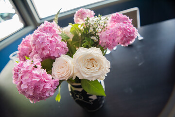 Pink hydrangeas and white roses in a vase as table centerpiece. Top view close up