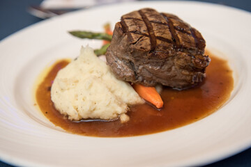 Filet mignon with mashed potatoes and vegetables on a white plate. Overhead view