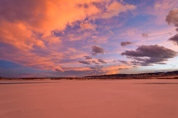 Winter Sunset - Colorful clouds rolling over a frozen mountain lake on a cold and windy winter evening. Chatfield State Park, Denver-Littleton, Colorado, USA.