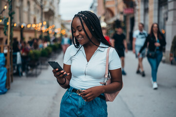 Cheerful african american woman using smartphone outside