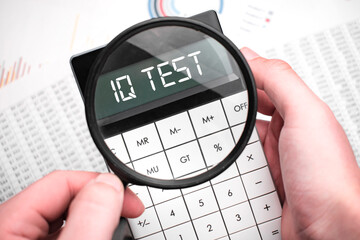 The word iq test is written on the calculator. Business man holding a calculator in his hand.