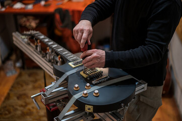 Fototapeta na wymiar Electrical guitar in repair service shop with a hands of a guitar luthier