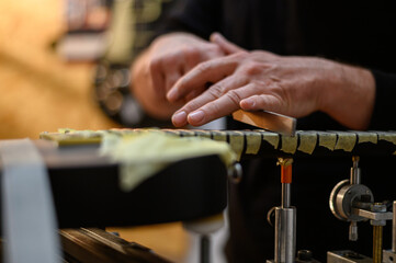 Master guitar luthier hands polishes the frets on the fretboard of the black electrical guitar
