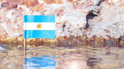 Argentina flag in water surface of the riverbank against defocused stone
