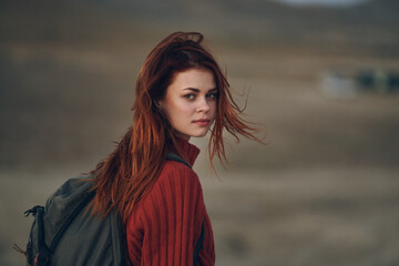 red-haired woman in the mountains with a backpack on her shoulders and fresh air travel copy space