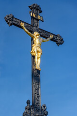 A iron cross with the crucified Jesus Christ on a background of blue sky