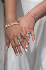 The left hands of two brides showing off their engagement and wedding rings on their wedding day....