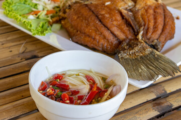 Traditional Thai food, grilled fish and soup on a bamboo table.