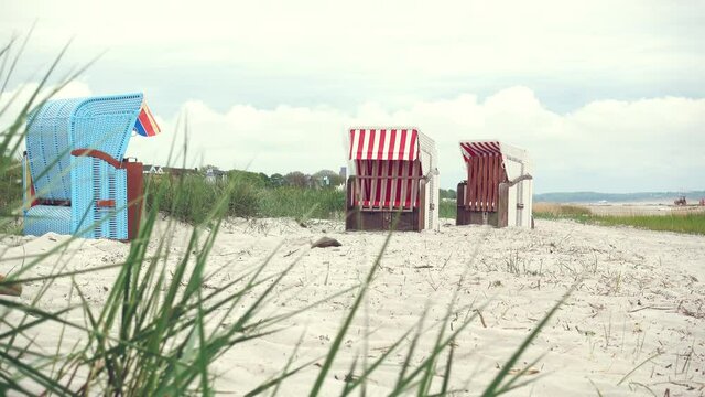 4K video of beach chair, white sand, and dunes at cloudy weather in north Germany