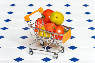 A shopping cart full of fruits and vegetables on the tiled floor.