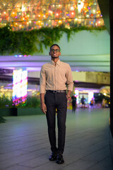 Full length shot of African businessman outdoors in city at night smiling