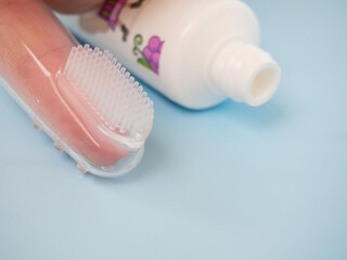 children's silicone tooth brush and paste on a blue background close-up, toothbrush on the finger