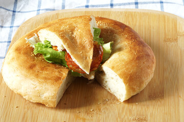 Traditional Central Asian bread is a tandoor flatbread. Sausage and salad sandwich in a piece of flatbread. Fast and delicious food.