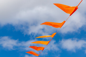 Selective focus of pennant orange flags hanging outside building with blue sky and white clouds as background, National holiday King’s Day or Koningsdag in Dutch, Netherlands. - Powered by Adobe