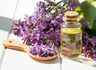 Obraz na płótnie Canvas Spa oil with lilac flowers. A bottle with aromatic oil and lilac flowers on a wooden background.copy space