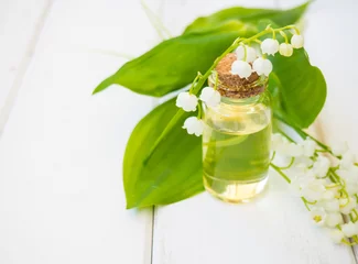 Küchenrückwand glas motiv Lily of the Valley, Convallaria majalis essential oil (extract, tincture, infusion, remedy) with fresh Convallaria flowers on a wooden background with space for text © Максим