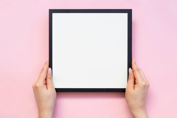 hand holding white frame on pink background