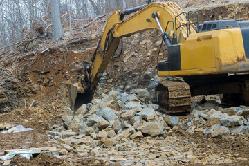 Fototapeta premium A large powerful loader overloads a pile of crawler excavator pours stones