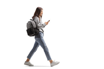 Full length profile shot of a female student walking with a mobile phone - obrazy, fototapety, plakaty