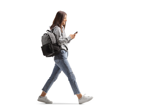 Full length profile shot of a female student walking with a mobile phone