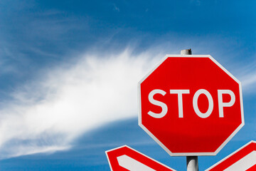 Bright red STOP sign on the road in front of the railway crossing
