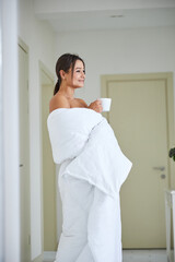 Gorgeous pretty elegant woman wrapped in quilt enjoying new day in the morning