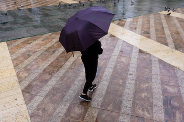 Mujer joven con un paraguas paseando por la ciudad en un dia lluvioso