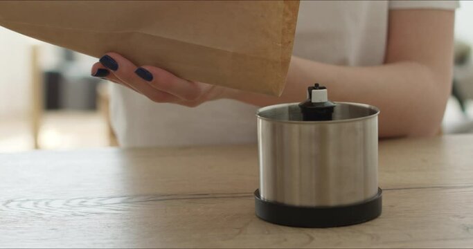hands put coffee beans in grinder