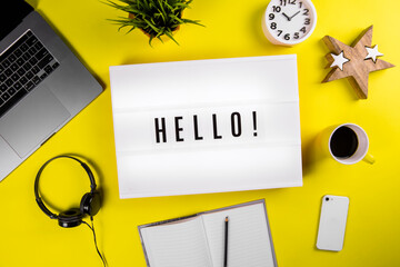 Lightbox with message HELLO on yellow background with laptop, smartphone, headphones and notes. Concept of office or student workspace, introduction business, beggining study, start education, lesson, © Model Republic