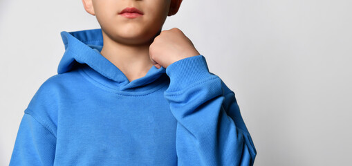 Close up detail of a blue sports hoodie dressed on a little boy. White background. Details of clothes for boys, sports suit for the schoolboy. Children's fashion concept. Place for text. Banner.