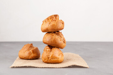 Fototapeta na wymiar Fresh french buns (profiteroles). Homemade baking, close-up. Light background, copy space