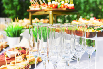 glasses on the table against the background of snacks before the start of the buffet in the open air