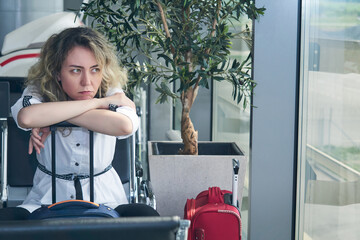 woman tourist with suitcases sits in the waiting room of the airport or train station and is bored