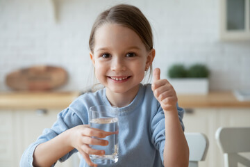 Portrait of happy little Caucasian girl child show thumb up recommend drinking clean pure mineral...