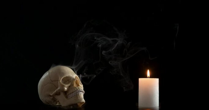 Skull for ceremony in the dark. A view of a skull for black caremony ritual and lighting white candle in the dark.