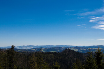 Obraz premium View of regular ordinary view from the mountain peak to green hills with a beautiful blue sky