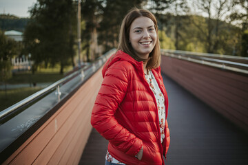 Young Caucasian female with short hair wearing a red jacket and walking on a street