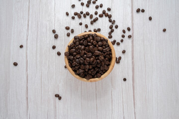 Coffee beans in wooden cup on wooden floor background.