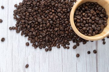 Coffee beans in wooden cup on wooden floor background.