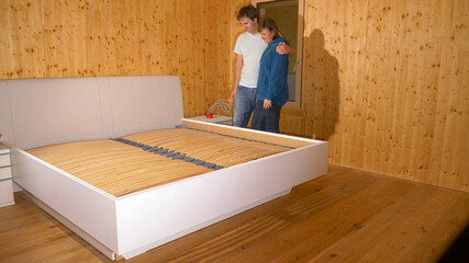 CLOSE UP: Young Caucasian couple hugs after assembling their king sized bed.