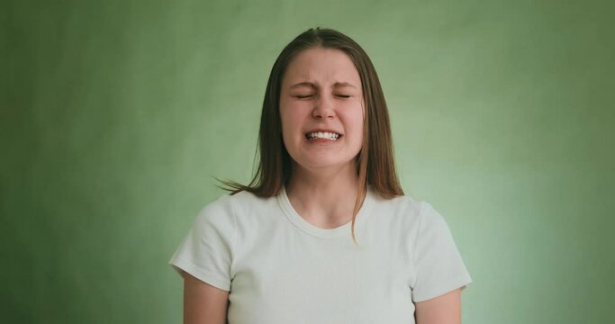 Despaired woman cries and yells with sad grimace on green