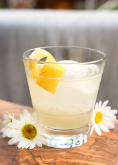 A Bee's Knees cocktail, vodka or gin with lemon and honey, garnished with lemon zest with some daisy's.