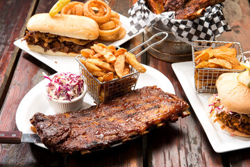 Barbecue restaurant food selection.  Barbecued pork ribs, beef ribs, pulled pork sandwich, and beef dip with home cut french fries.