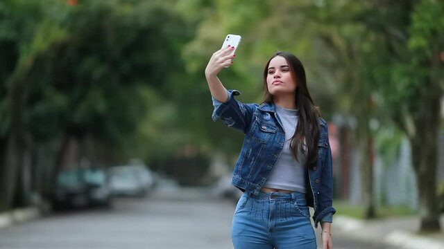 Young woman taking selfie with cellphone. Girl takes photo of herself with phone