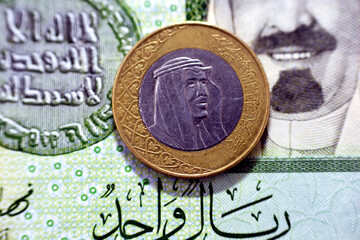 One Saudi Arabia riyal coin (obverse side) year 2016 on 1 Saudi riyal paper banknote background,...