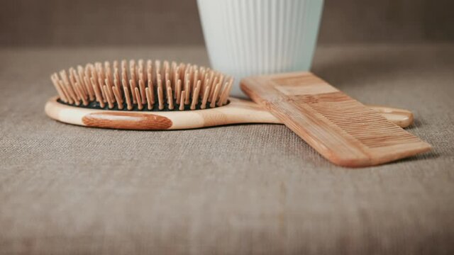 Eco style in the bathroom. A view of a bamboo toothbrush into a glass by the combs on the table.